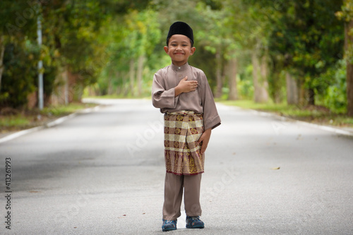 A Malay boy in Malay traditional cloth showing his happy reaction during Eid Fitri or Hari Raya celebration.