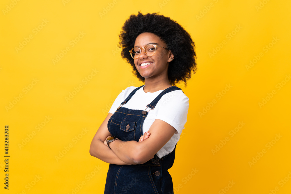 Young African American woman isolated on yellow background with arms crossed and looking forward Young African American woman isolated on yellow background with arms crossed and looking forward