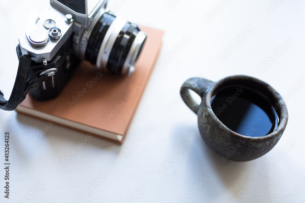 Cup of tea or coffee in a mug with a book and vintage camera.