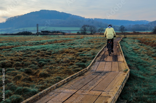Man riding bicycle on the wooden footpath in Seaton Wetlands Devon