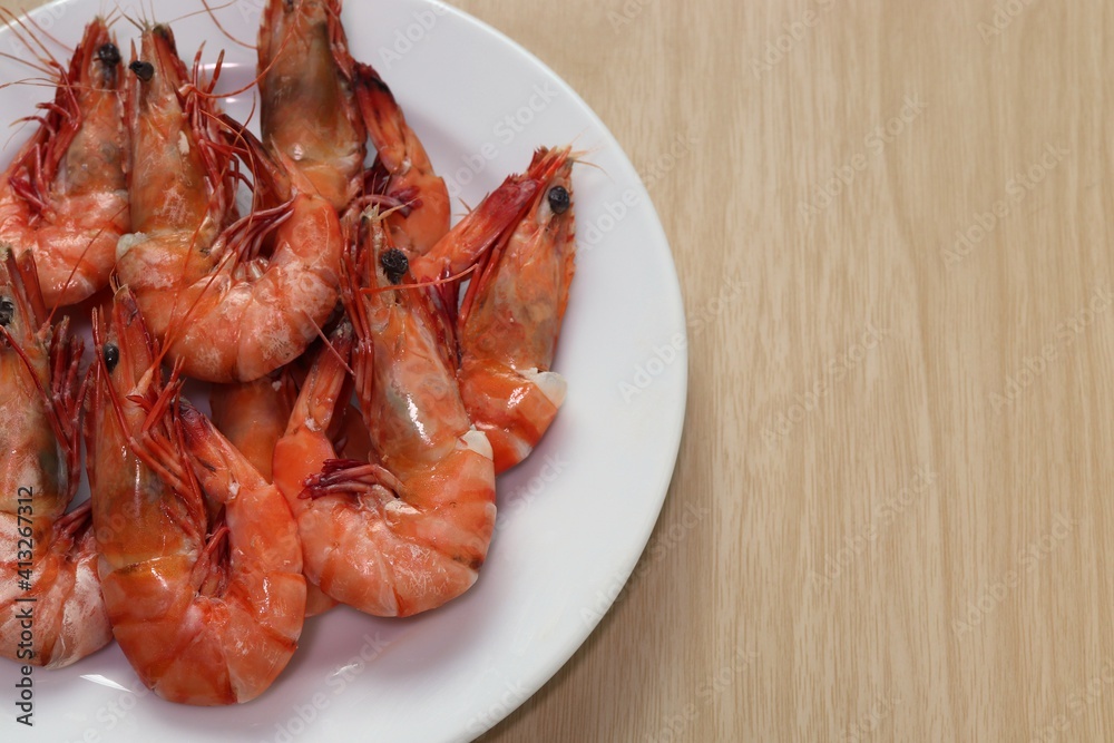 Boiled shrimp in white plate on brown wooden background Boiled shrimp in white plate on brown wooden background