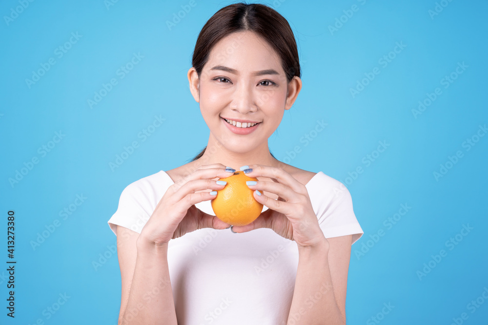 Young beautiful asian woman holding a orange, Isolated on blue background. Young beautiful asian woman holding a orange, Isolated on blue background.
