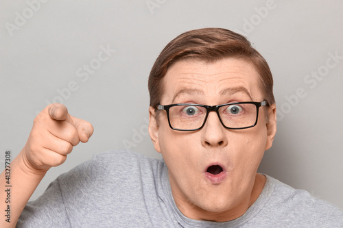 Portrait of shocked man pointing with finger at something unbelievable