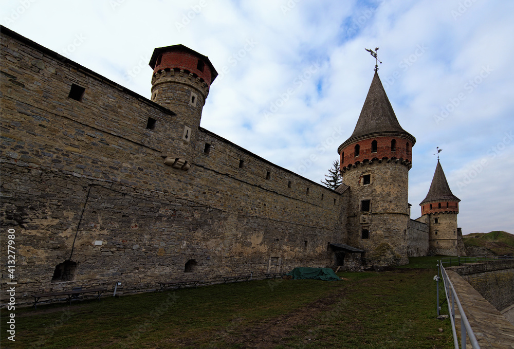 Landscape photo of ancient Kamianets-Podilskyi Castle. High and thick stone walls with towers against blue sky. Abstract photo of stone walls. Major tourist attraction in Kamianets-Podilskyi, Ukraine