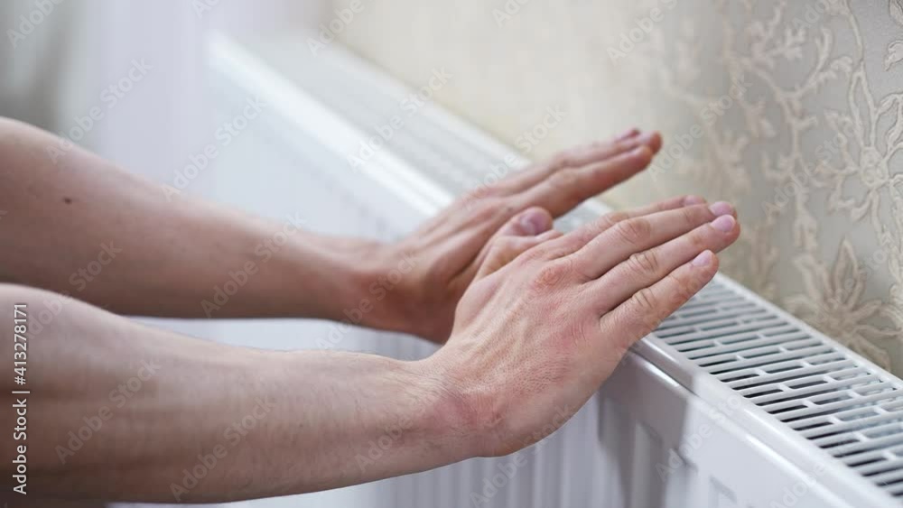 Man checks the temperature of the heating radiator Man checks the temperature of the heating radiator