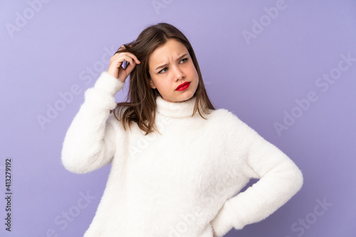 Teenager girl isolated on purple background having doubts and with confuse face expression