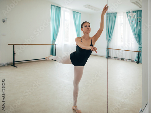 Ballerina is doing classical ballet near mirror