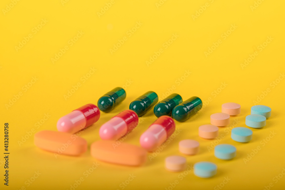 Assorted pharmaceutical medicine pills, tablets and capsules over yellow background. High number of pills on surface. High resolution image for pharmaceutical industry. Assorted pharmaceutical medicine pills, tablets and capsules over yellow background. High number of pills on surface. High resolution image for pharmaceutical industry.
