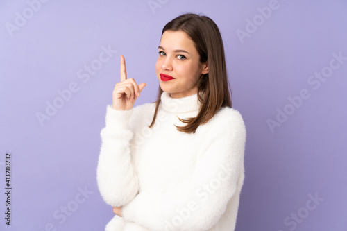 Teenager girl isolated on purple background showing and lifting a finger in sign of the best