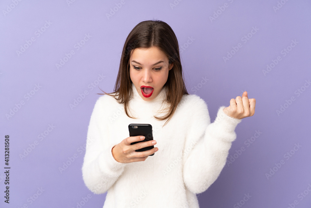 Teenager girl isolated on purple background surprised and sending a message Teenager girl isolated on purple background surprised and sending a message