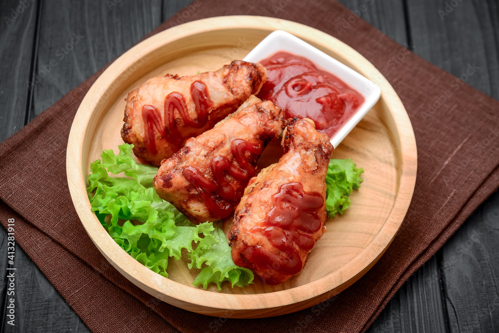 Chicken wings with ketchup on a wooden table.