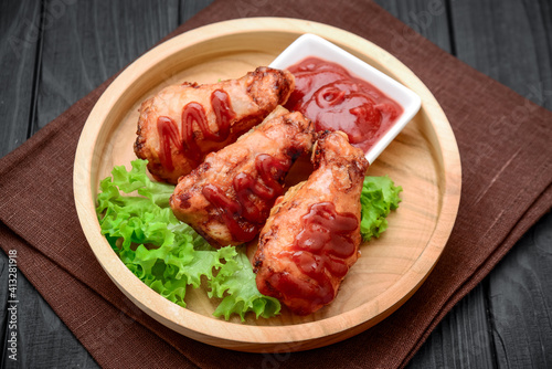 Chicken wings with ketchup on a wooden table.