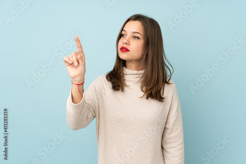 Teenager girl isolated on blue background touching on transparent screen