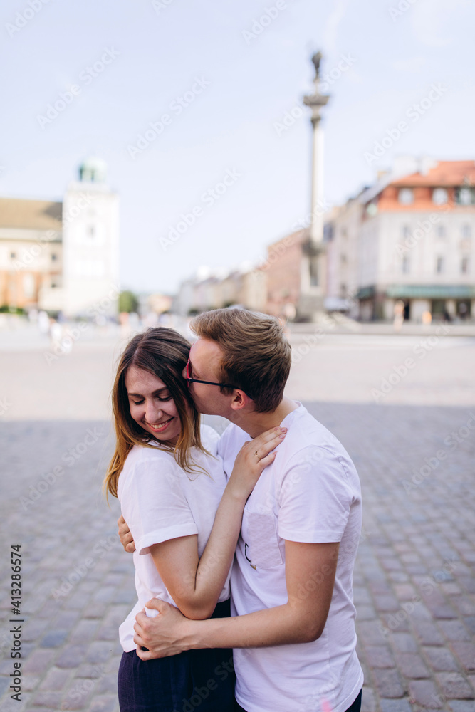 A young couple travels through the city square on a sunny day. Old district of the European capital.