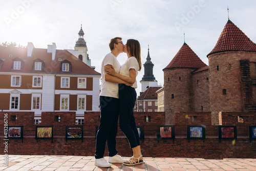 A young couple travels through the city square on a sunny day. Old district of the European capital.