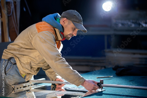 Photos A working person in a furniture industry is cutting a mirror with a glass cutter