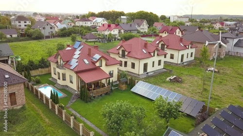 Wallpaper Mural Aerial view of suburban homes and private house with green grass covered yard, solar panels on roof, swimming pool with blue water and wind turbine generator. Torontodigital.ca