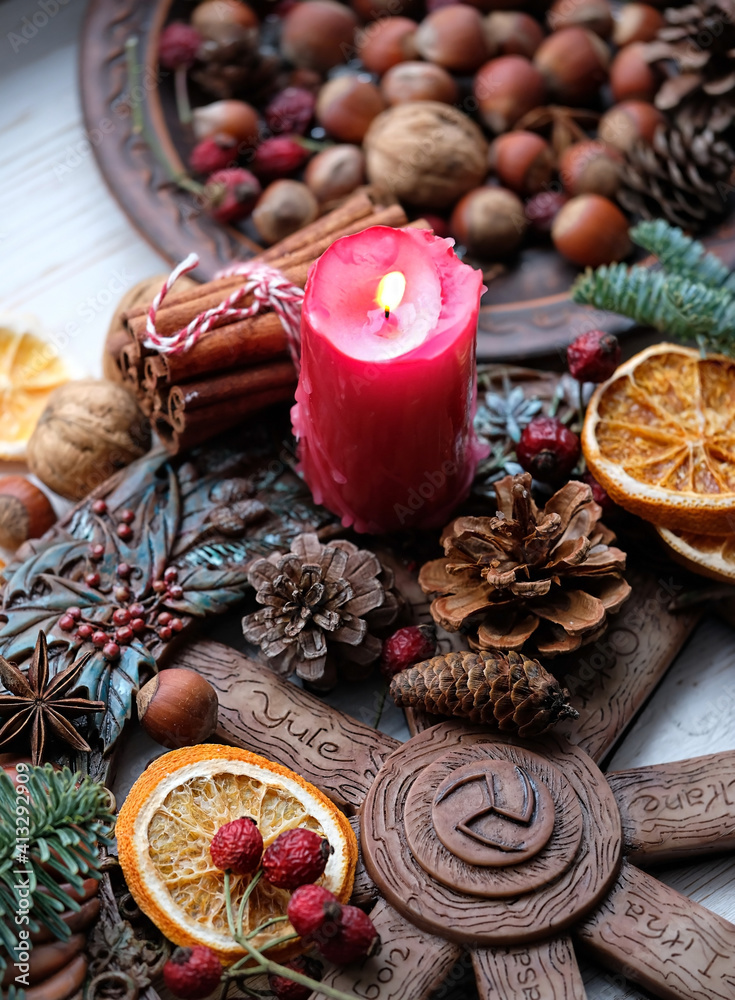 Winter altar for Yule sabbath. pagan holiday. Red candle, wheel of the year, cinnamon, nuts, cones, dry orange slices. Witchcraft Esoteric Ritual for Christmas, Yule, Magical Winter Solstice.