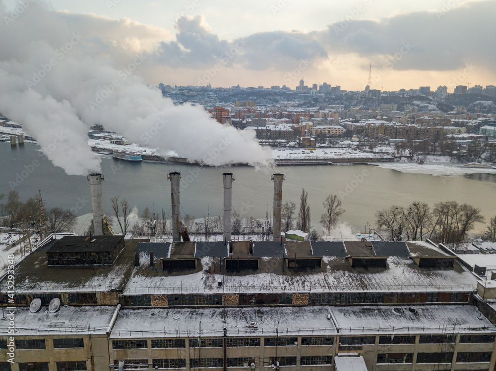 Fuming chimneys of a power plant. Aerial drone view. Winter snowy evening.