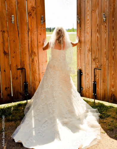 Bride in Wedding Dress Opening Barn Doors to Sunny Day