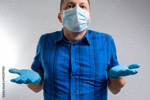фотографія Middle aged handsome man wearing medical mask clueless and confused expression with arms and hands raised