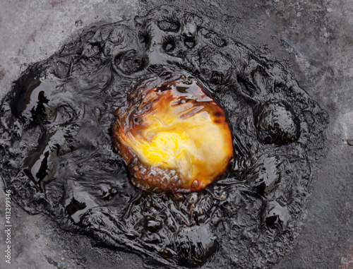 Overhead macro shot: an egg that has been cooking for too long in the pan, turned into a mess.
