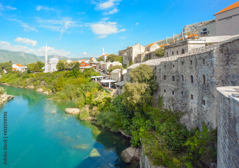 The river Neretva flows by the ancient wall surrounding the old town and village of Mostar, Bosnia and Herzegovina.