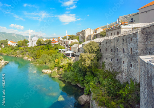 The river Neretva flows by the ancient wall surrounding the old town and village of Mostar, Bosnia and Herzegovina.