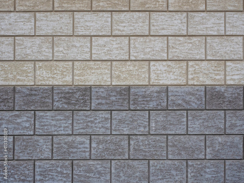 Wall cladding in rough gray and beige tiles imitating masonry. Not seamless texture