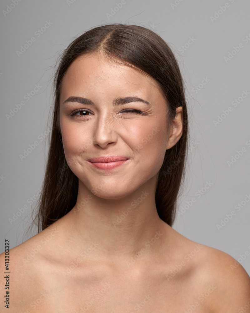 Young beautiful female model close-up studio beauty portrait. Girl with natural make-up and long brunette straight hair. Happy crazy woman shoing her tongue and winking Young beautiful female model close-up studio beauty portrait. Girl with natural make-up and long brunette straight hair. Happy crazy woman shoing her tongue and winking