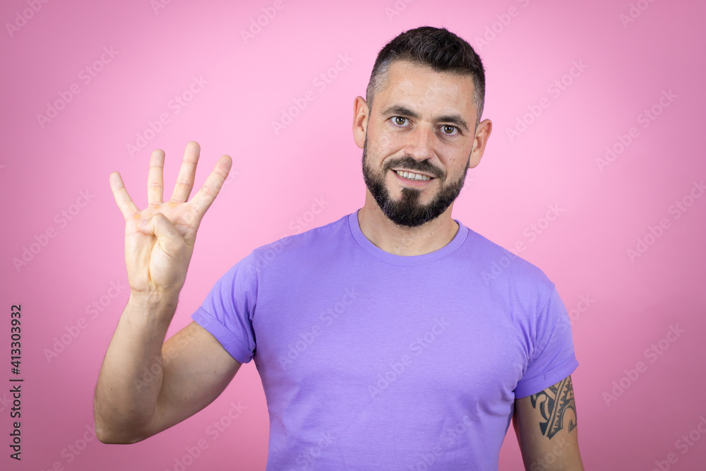 Young handsome man wearing casual t-shirt over pink background showing and pointing up with fingers number four while smiling confident and happy Young handsome man wearing casual t-shirt over pink background showing and pointing up with fingers number four while smiling confident and happy
