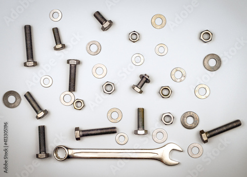 Texture with bolts, nuts, washers and wrench on a gray background