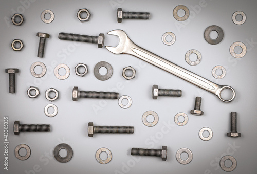 Bolts, nuts, washers and wrench on a gray background