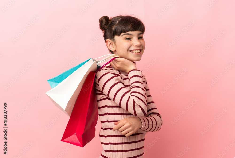 Little caucasian girl isolated on pink background holding shopping bags and smiling Little caucasian girl isolated on pink background holding shopping bags and smiling