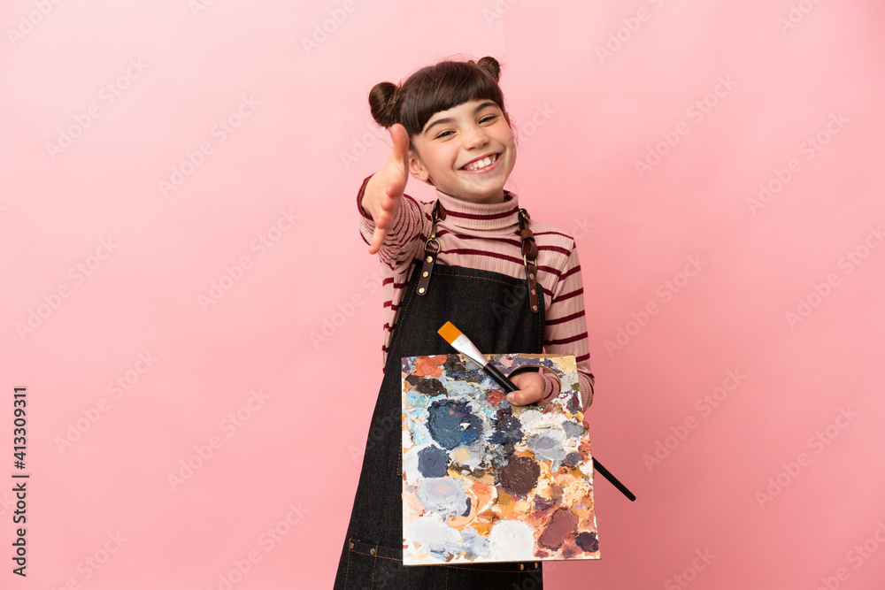 Little artist girl holding a palette isolated on pink background shaking hands for closing a good deal Little artist girl holding a palette isolated on pink background shaking hands for closing a good deal