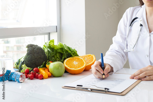 Female nutritionist doctor writing vegetable diet plan photo