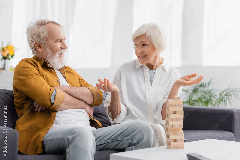 Senior woman talking with husband near blocks wood game on blurred foreground