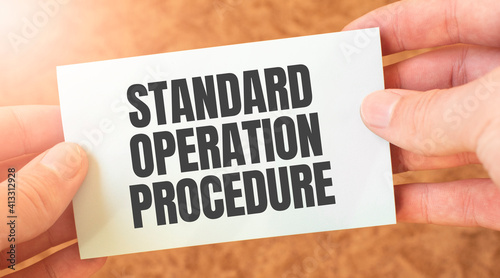 Standard Operation Procedure word inscription on white card paper sheet in hands of a businessman. recap concept. red and white paper