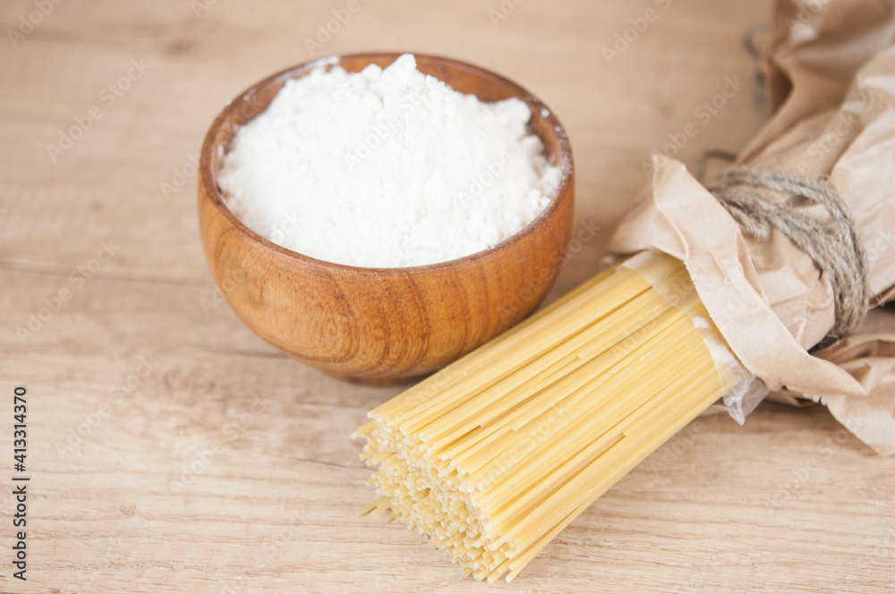 Spaghetti pasta with flour in wood bowi on wooden table Spaghetti pasta with flour in wood bowi on wooden table
