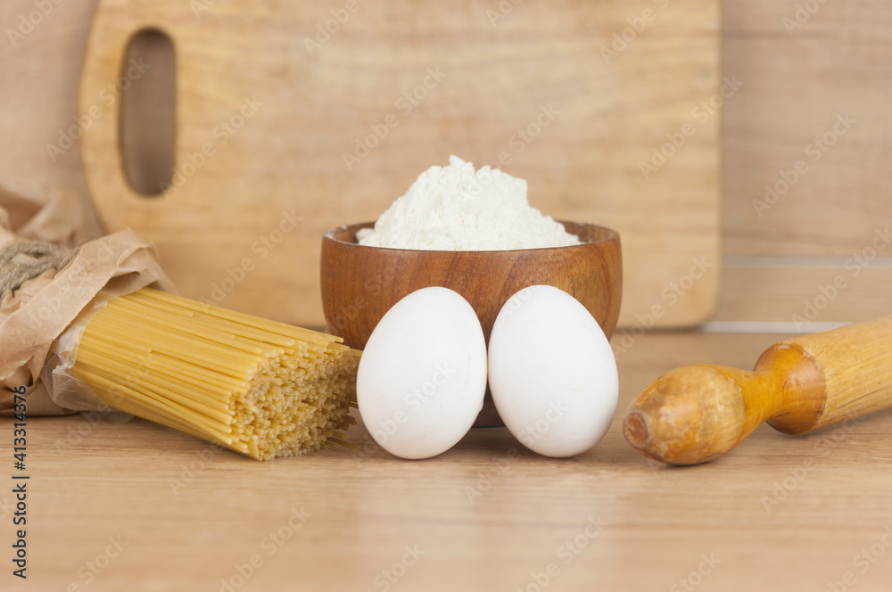 Spaghetti pasta dought with eggs, flour and rolling pin on wooden table Spaghetti pasta dought with eggs, flour and rolling pin on wooden table