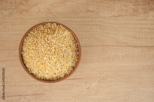 wheat groats in a wooden bowl on a wooden table background