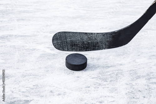 Black hockey stick and rubber puck on ice background. Closeup. Front view. photo