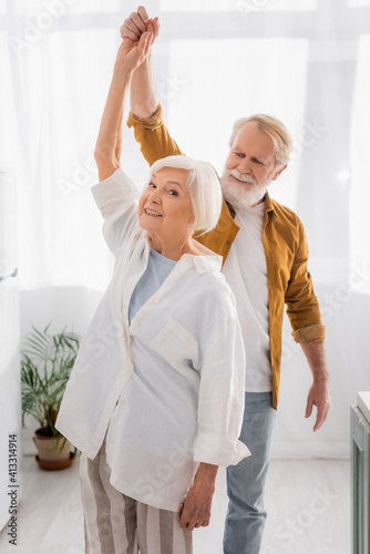 Senior couple dancing and smiling in kitchen