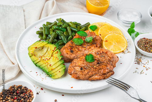 Fried chicken breast, avocado, beans and lemon on a light background. Side view, horizontal. Healthy food.