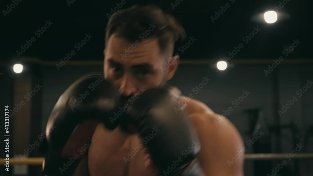 Hispanic shirtless man in boxing gloves working out on boxing ring