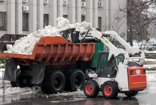 loading snow into a truck on a city street in winter