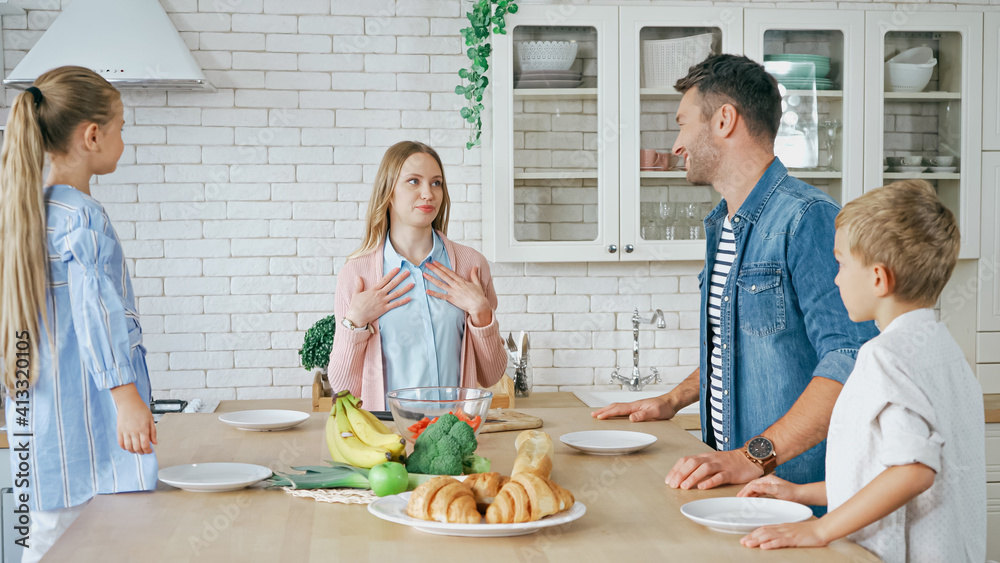 Woman standing near family and food on kitchen table