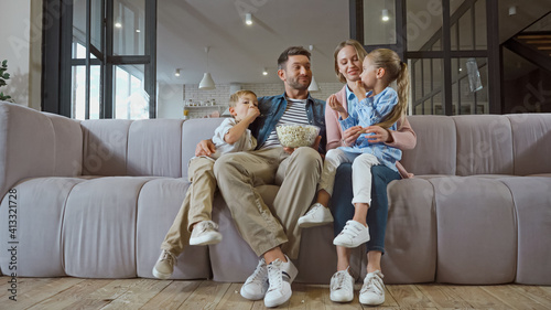 Smiling family with popcorn sitting on couch