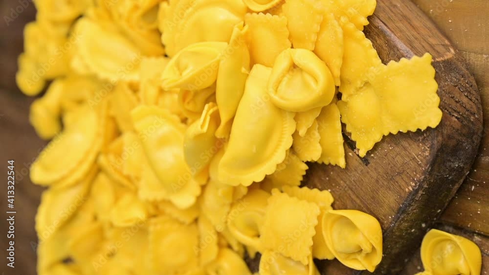 Tartollini with cheese or meat for cooking in broth, different shapes. Traditional dish for celebrations in italy, Emilia Romagna region. Fresh homemade pasta with filling on a wooden table. vertical Tartollini with cheese or meat for cooking in broth, different shapes. Traditional dish for celebrations in italy, Emilia Romagna region. Fresh homemade pasta with filling on a wooden table. vertical