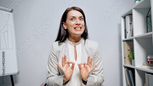 Smiling businesswoman showing ok gesture during video call in office